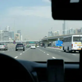 القيادة على طريق دبي السريع مع أفق المدينة.