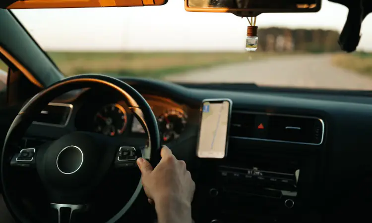 A Person Driving a Car with a Map on Smartphone