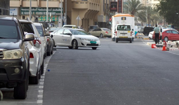 Street view in Sharjah, UAE with cars and buildings.