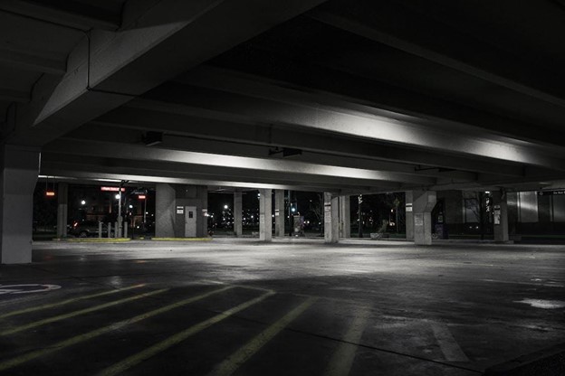 An empty urban parking garage at night with dramatic lighting creating a moody atmosphere.