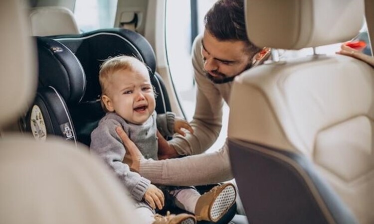 Father putting daughter in a car seat.