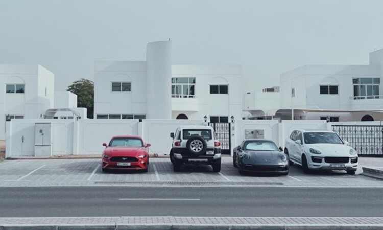 Three cars parked in a parking lot next to a building in Dubai