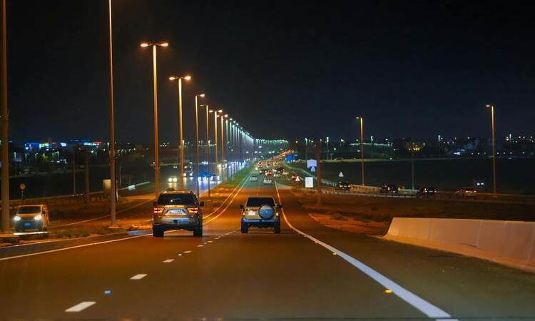 Illuminated highway in Abu Dhabi with cars and streetlights at night.